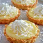 Delicious coconut cream tart topped with fresh coconut flakes and whipped cream