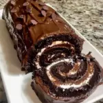 Decadent chocolate cake roll topped with rich chocolate ganache and decorations.