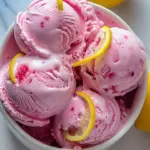 Creamy pink lemonade ice cream in a bowl with a lemon slice