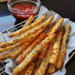 Plate of golden crispy Parmesan potato fries with herbs and seasoning