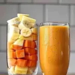 Delicious orange pineapple carrot smoothie in a glass with fresh ingredients