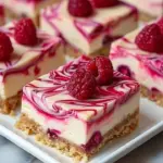 Raspberry swirl cheesecake squares on a wooden serving board