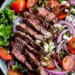 Delicious Steak and Gorgonzola Salad topped with fresh greens and grilled beef strips