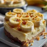 Slice of velvety banana cheesecake topped with fresh banana slices and whipped cream