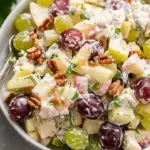A vibrant Waldorf Salad with apples, walnuts, celery, and grapes in a creamy dressing.
